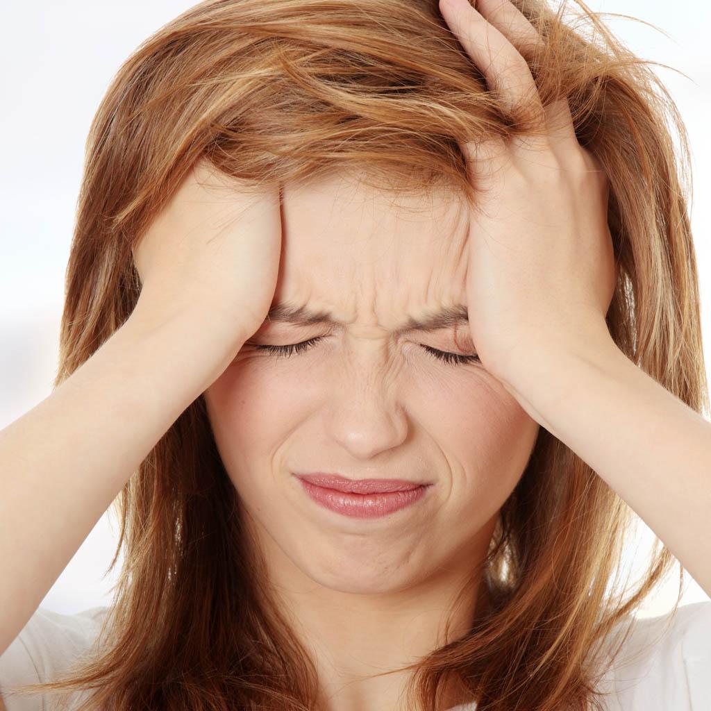 Een persoon houdt hun hoofd vast, zichtbaar lijdend aan een migraine.