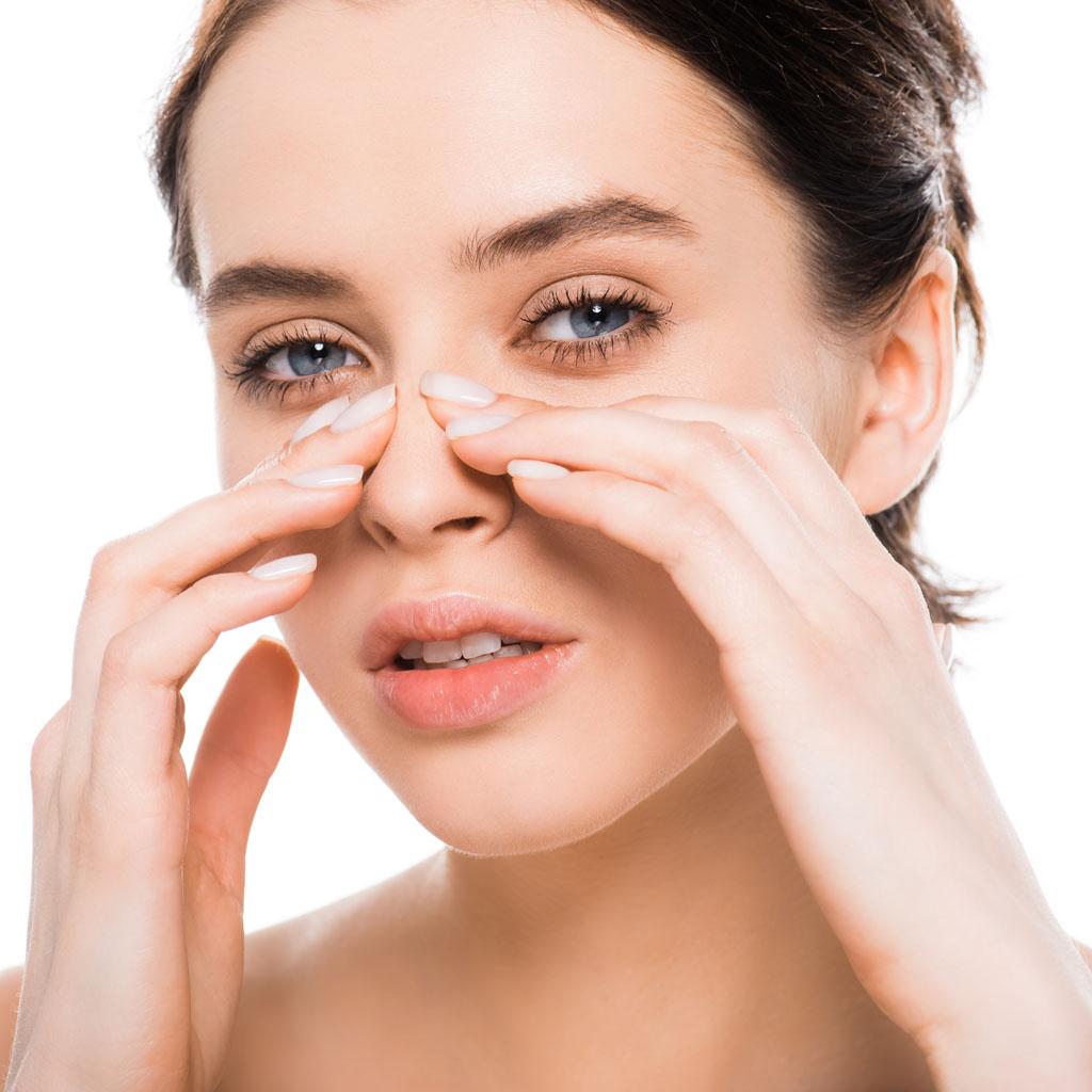 Alt text: Woman sitting with bandaged nose after rhinoplasty surgery.