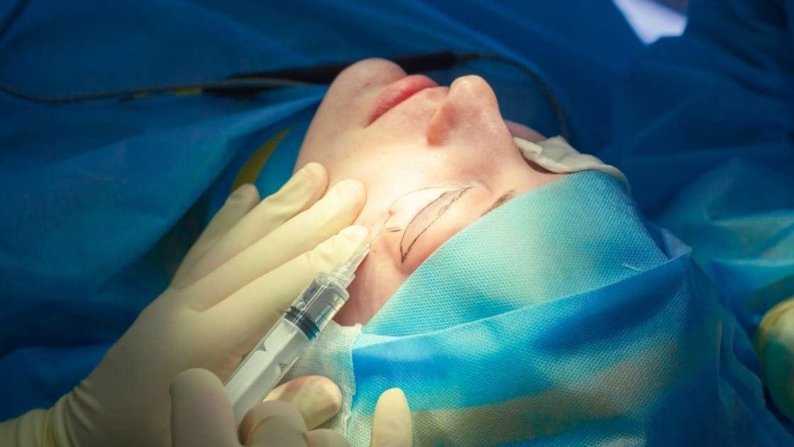 Surgical procedure of drooping eyelid, hands of doctors performing surgery.